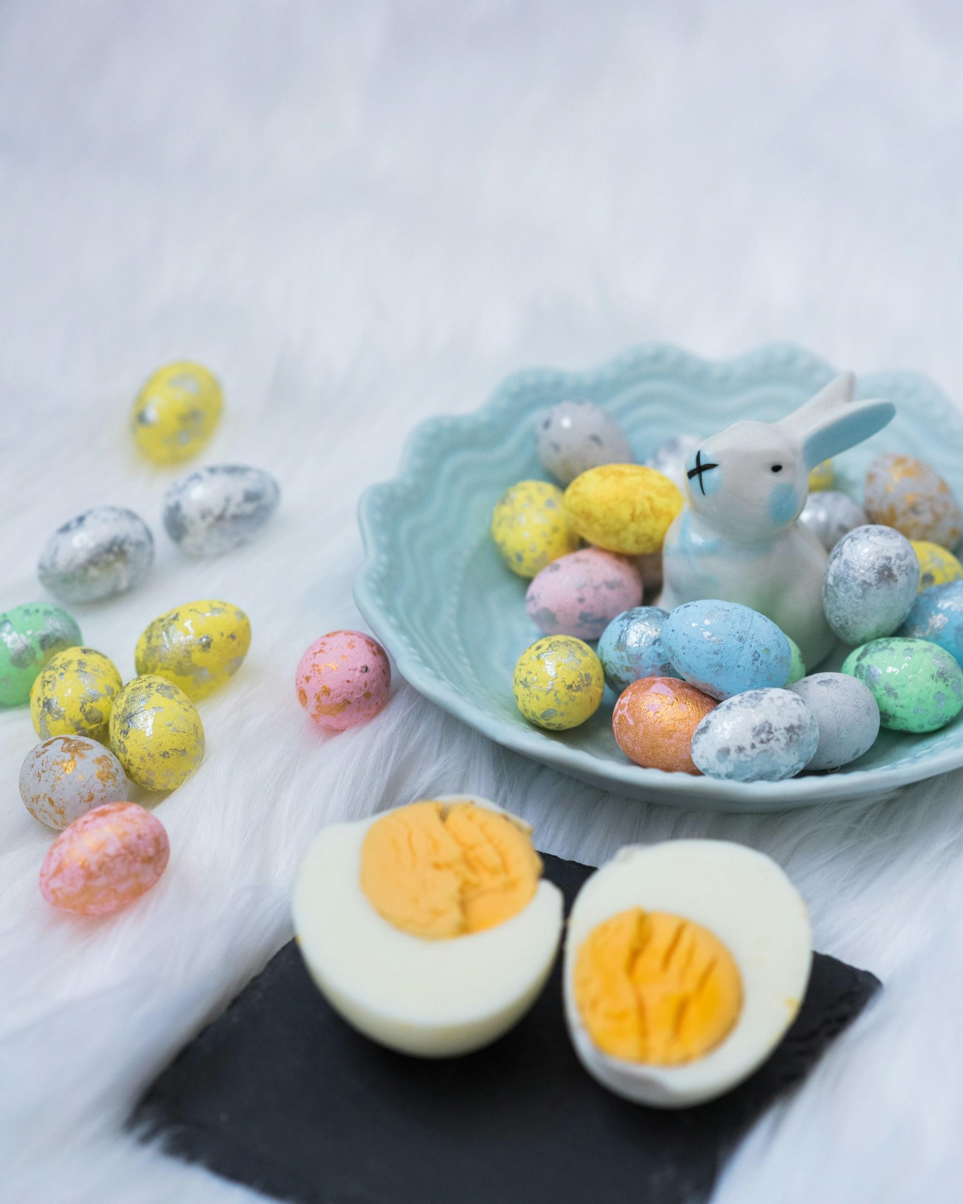 A plate of chocolate Easter eggs and a hardboiled egg, cut in half. 