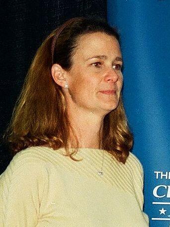 A woman with brown hair wearing a yellow shirt.