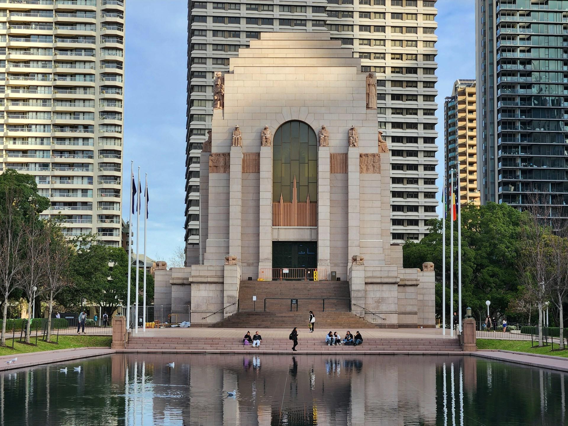 A large decorative building in front of water on a sunny day.