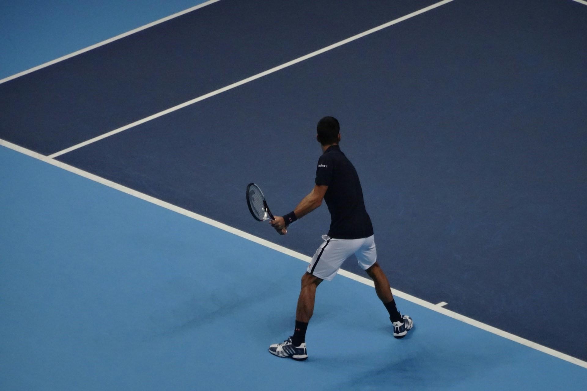 A man playing on a hard court.