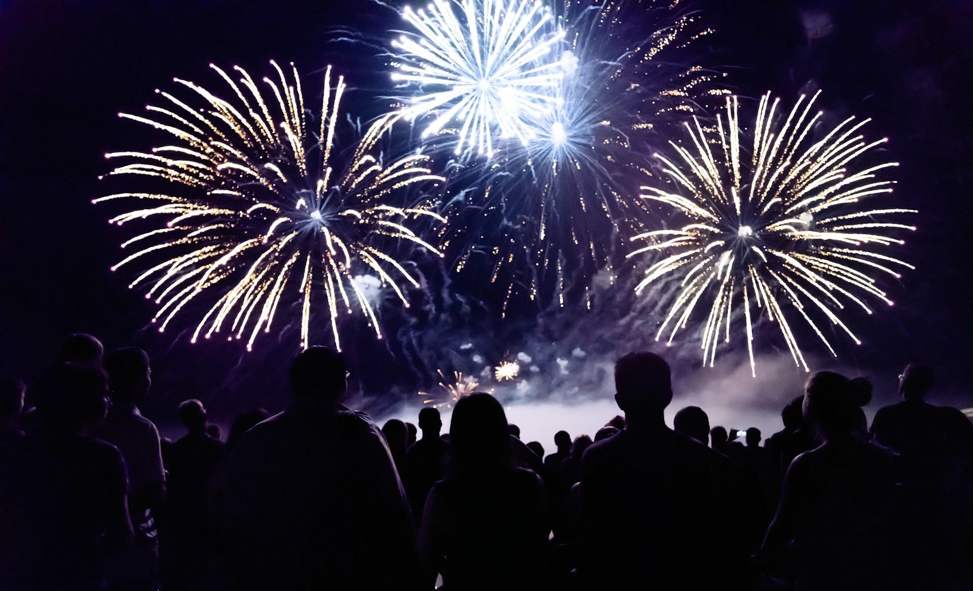 A fireworks display at night, with a crowd of people watching.