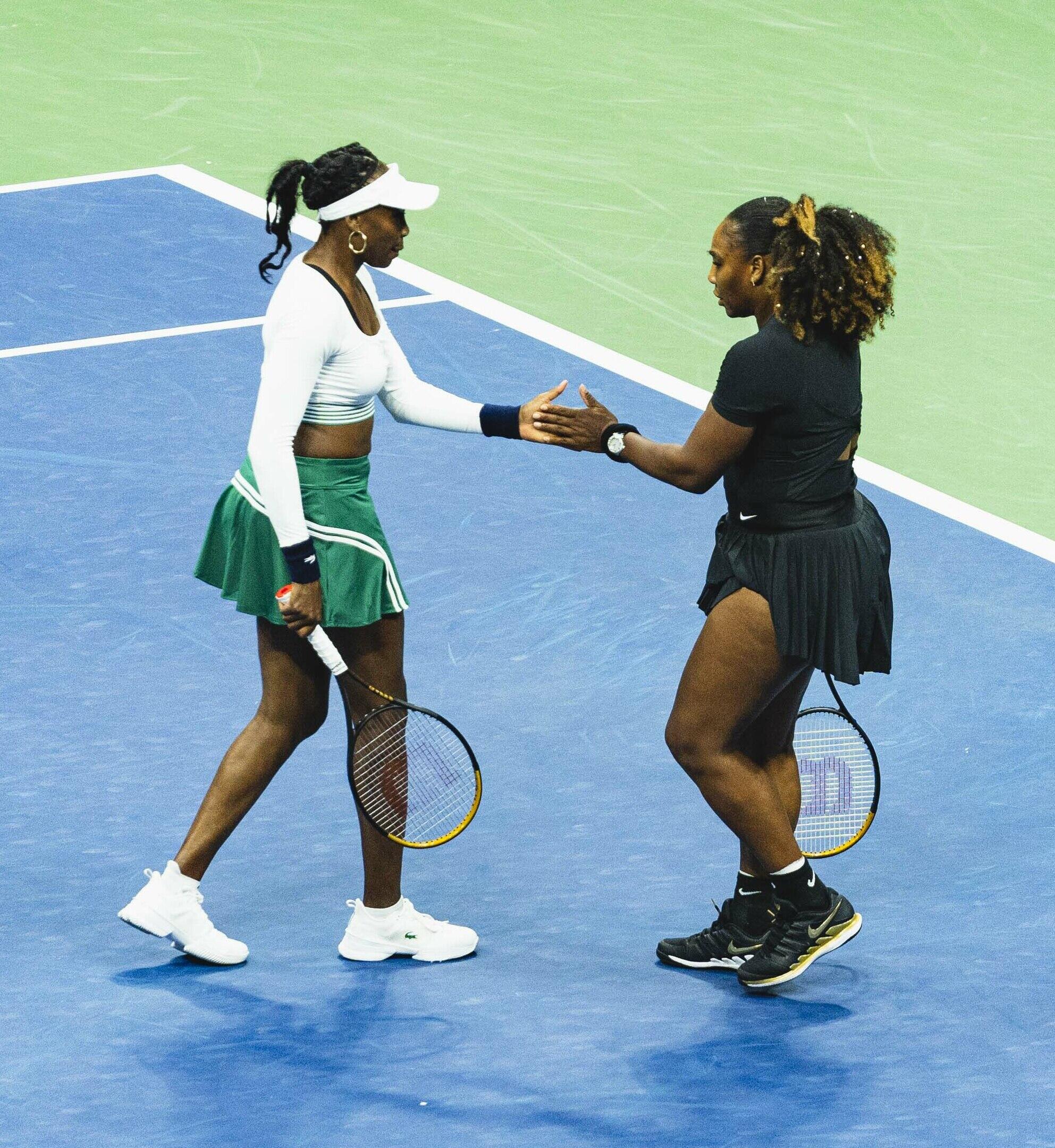 Two women on a tennis court shaking hands.