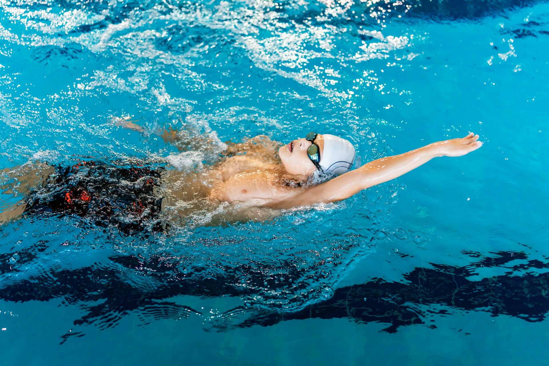 A person wearing a swim cap and goggles in a pool.