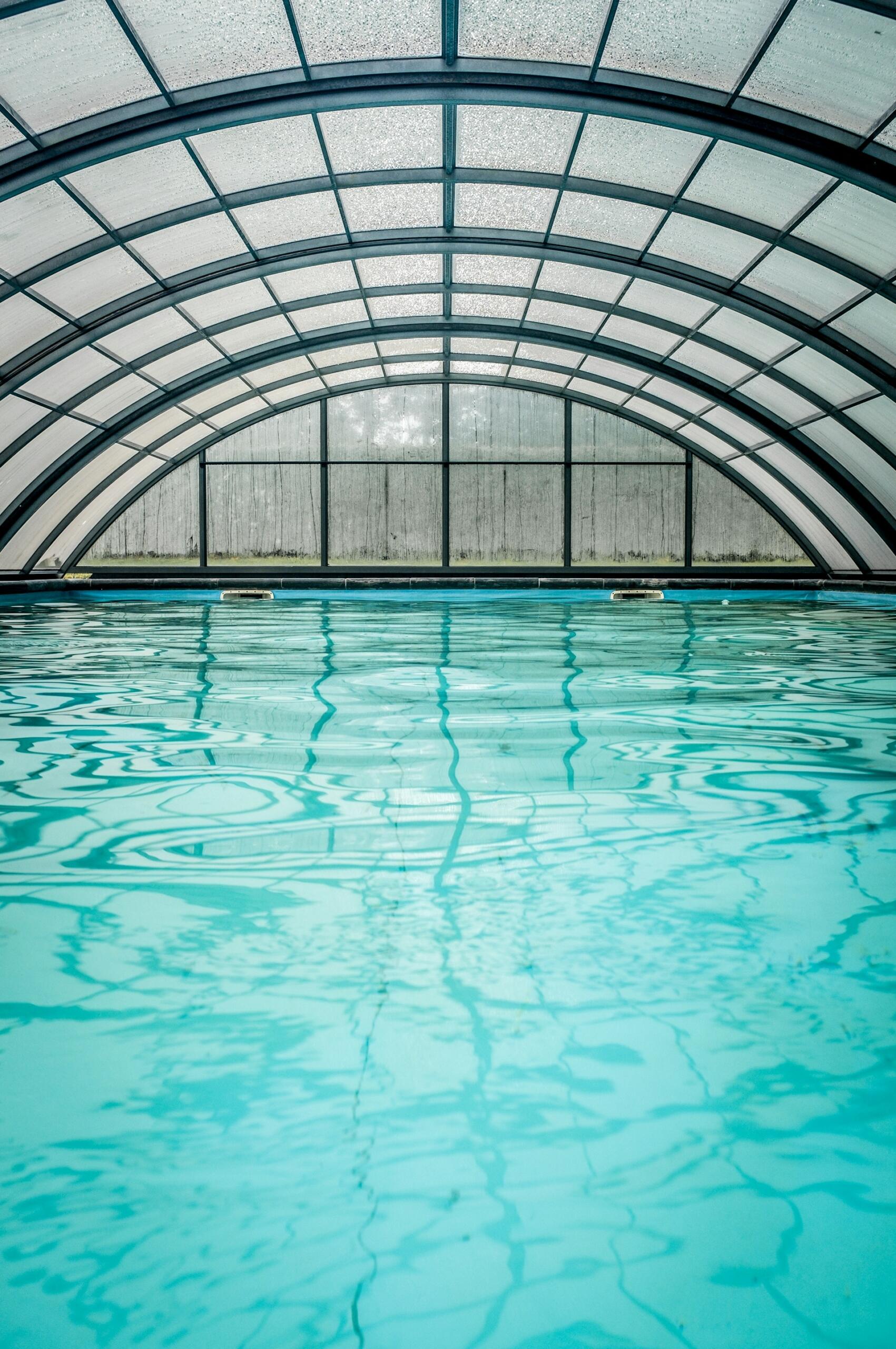 An indoor swimming pool with an arched glass ceiling.