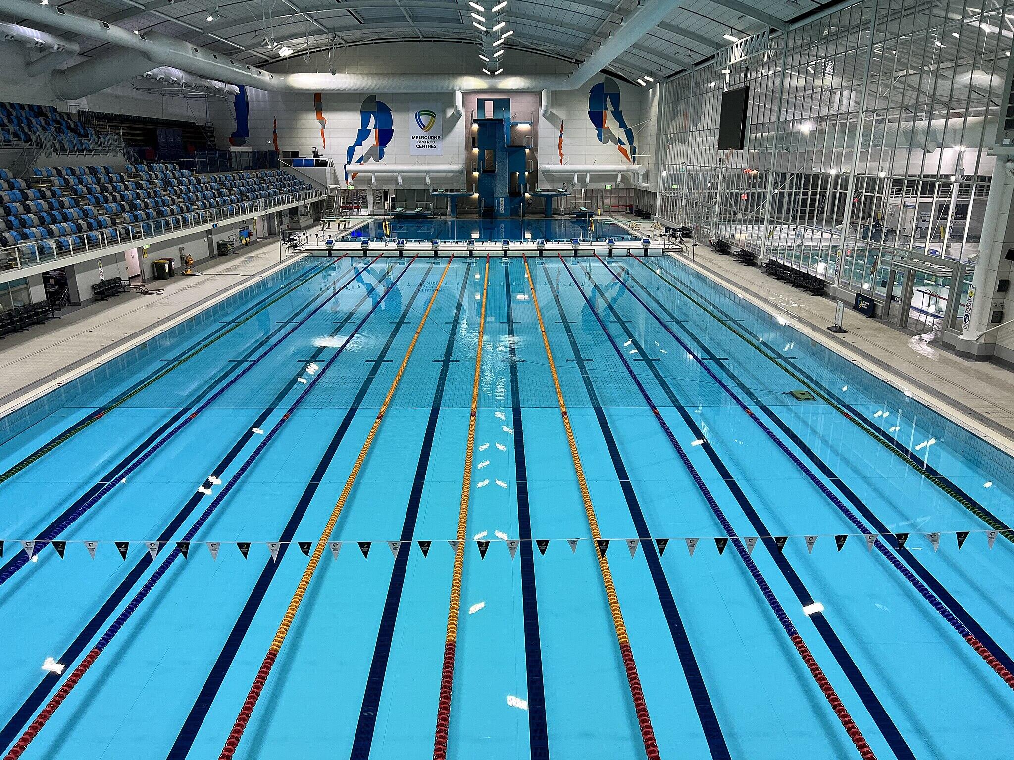 An indoor pool with bleachers and art on the walls.