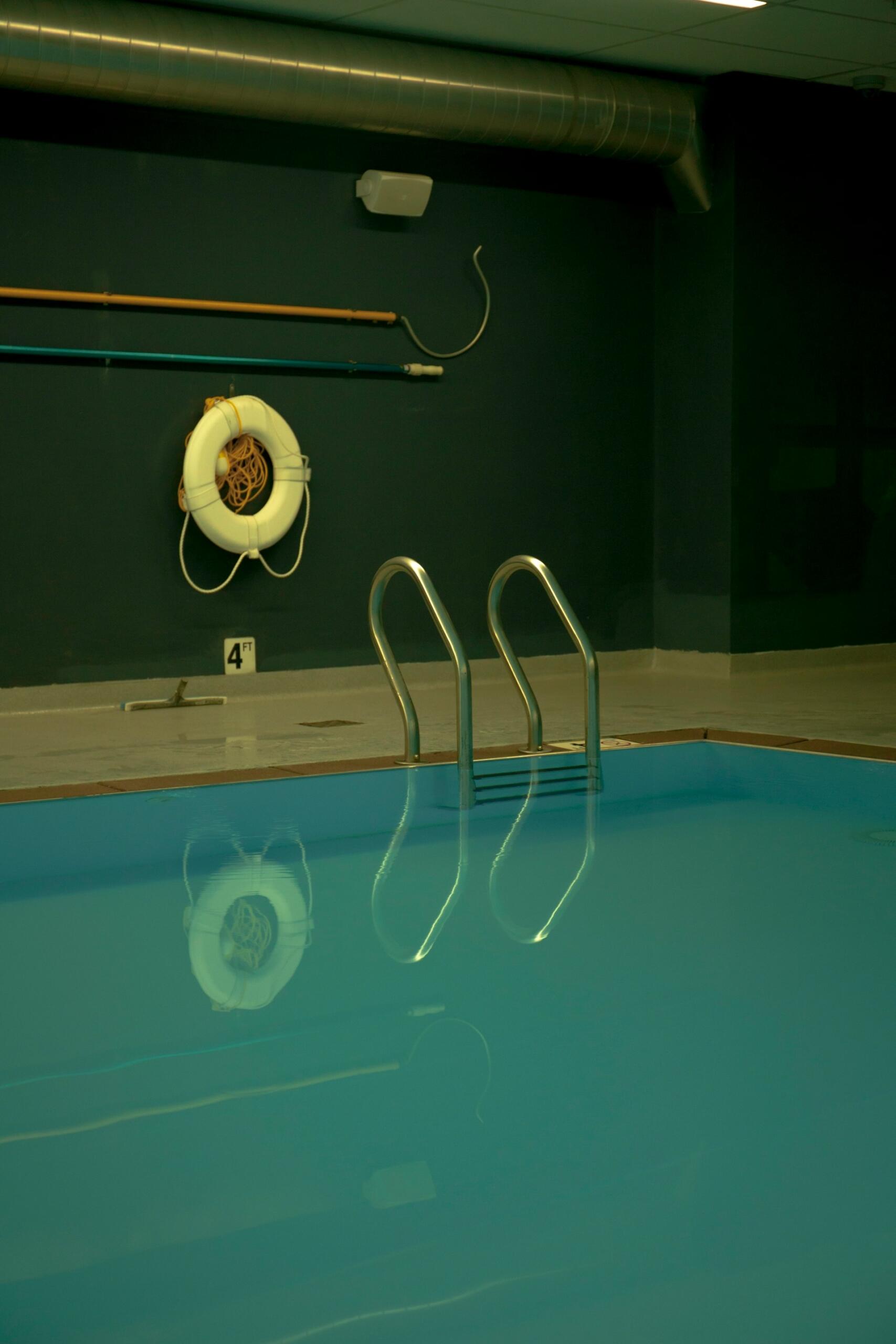 An indoor pool with safety equipment hanging on the wall.