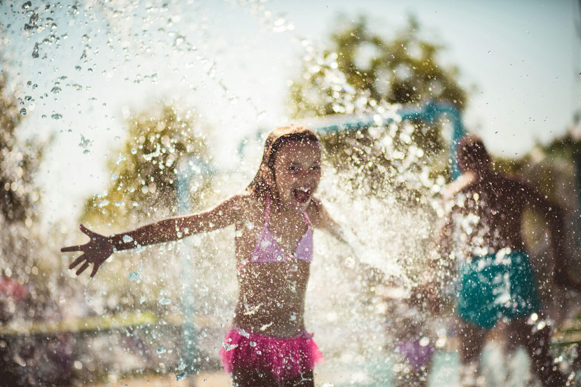 A child splashes in an outdoor pool on a sunny day.