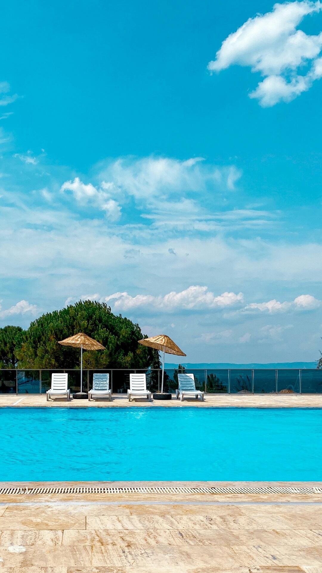 A swimming pool with trees in the distance on a sunny day.