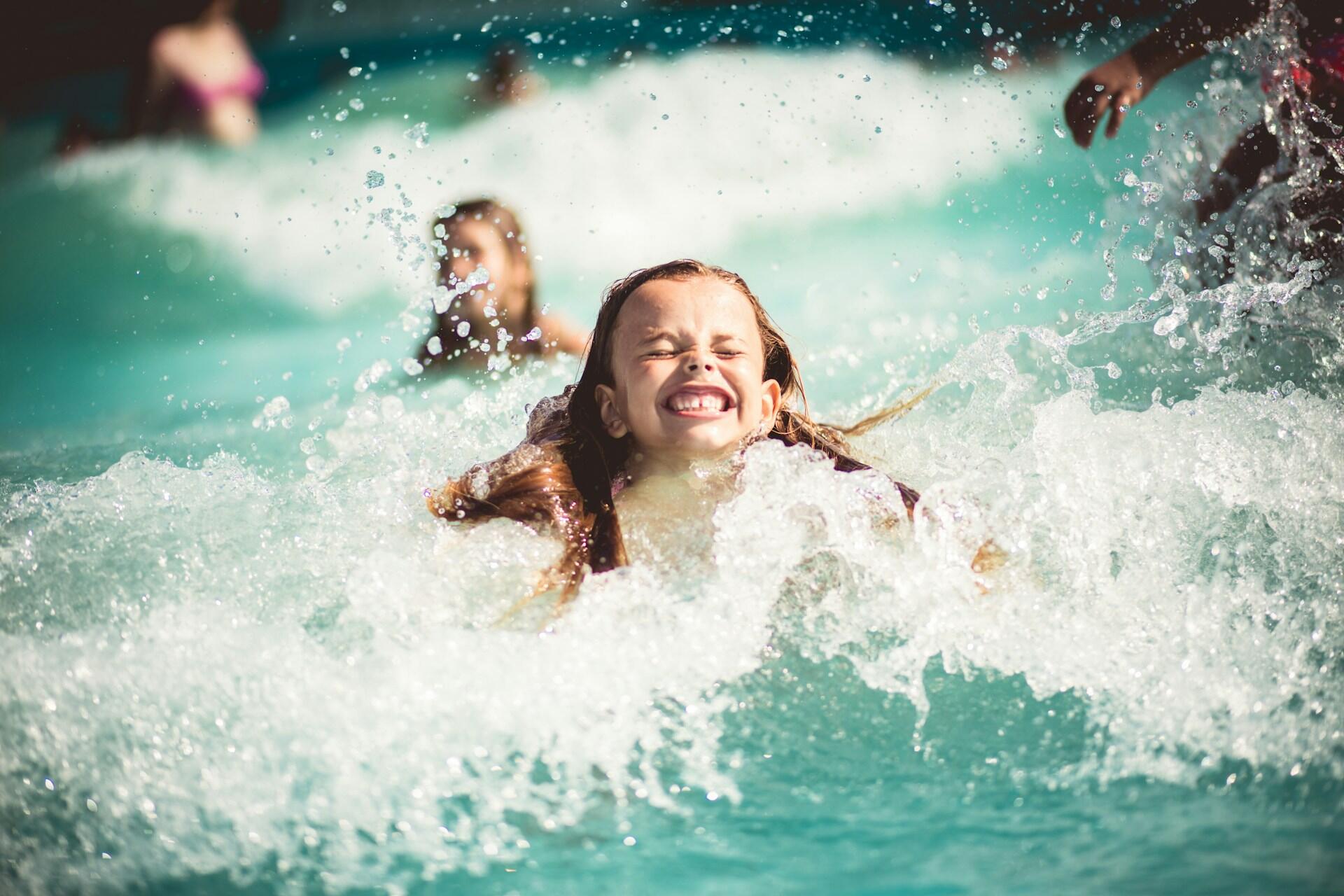 Children playing in a pool on a sunny day.