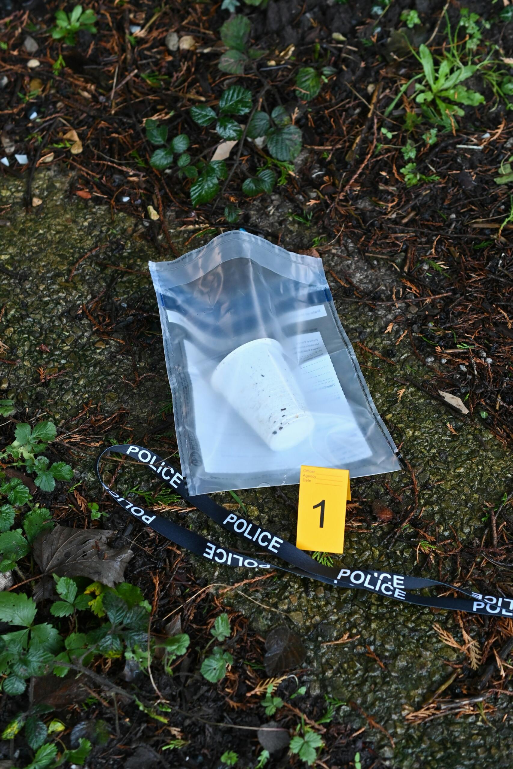 A cup in a clear plastic bag laying on the ground.