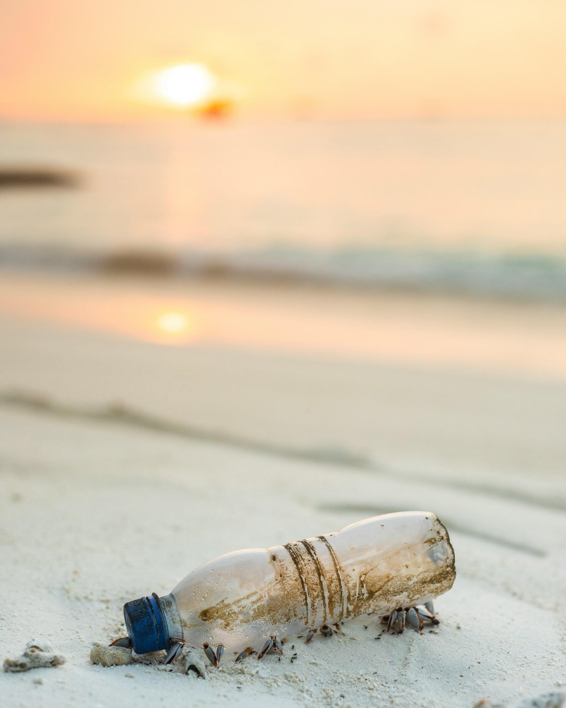 A beach with a plastic bottle on it.