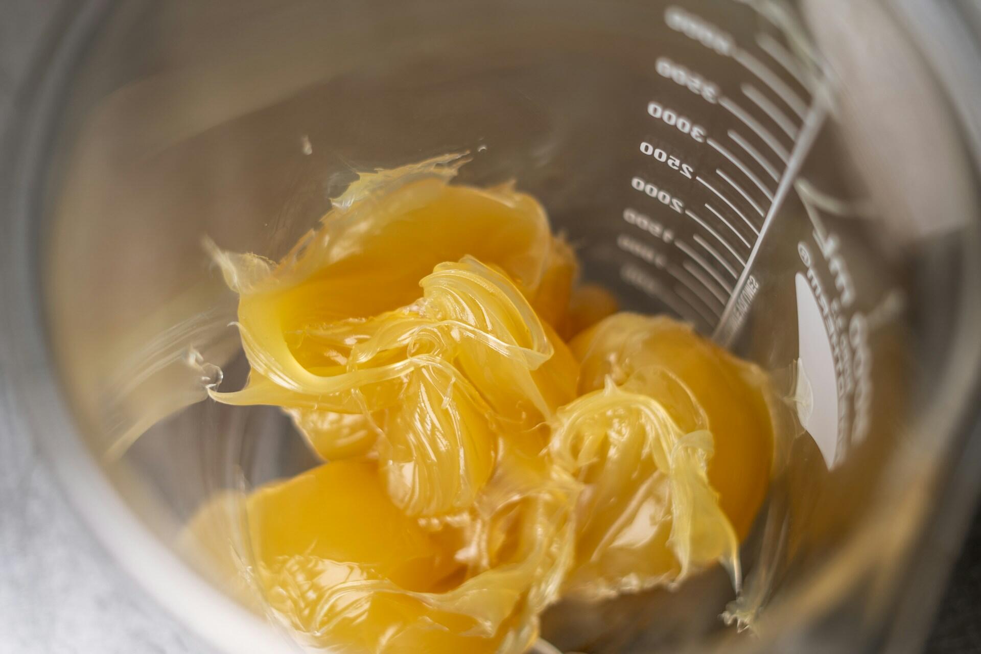 A yellow waxy substance in a measuring glass.