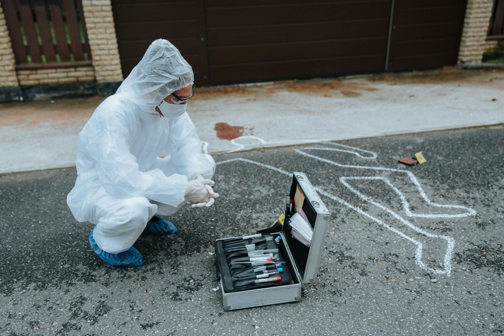 a forensic scientist wearing full PPE prepares to get samples from a crime scene