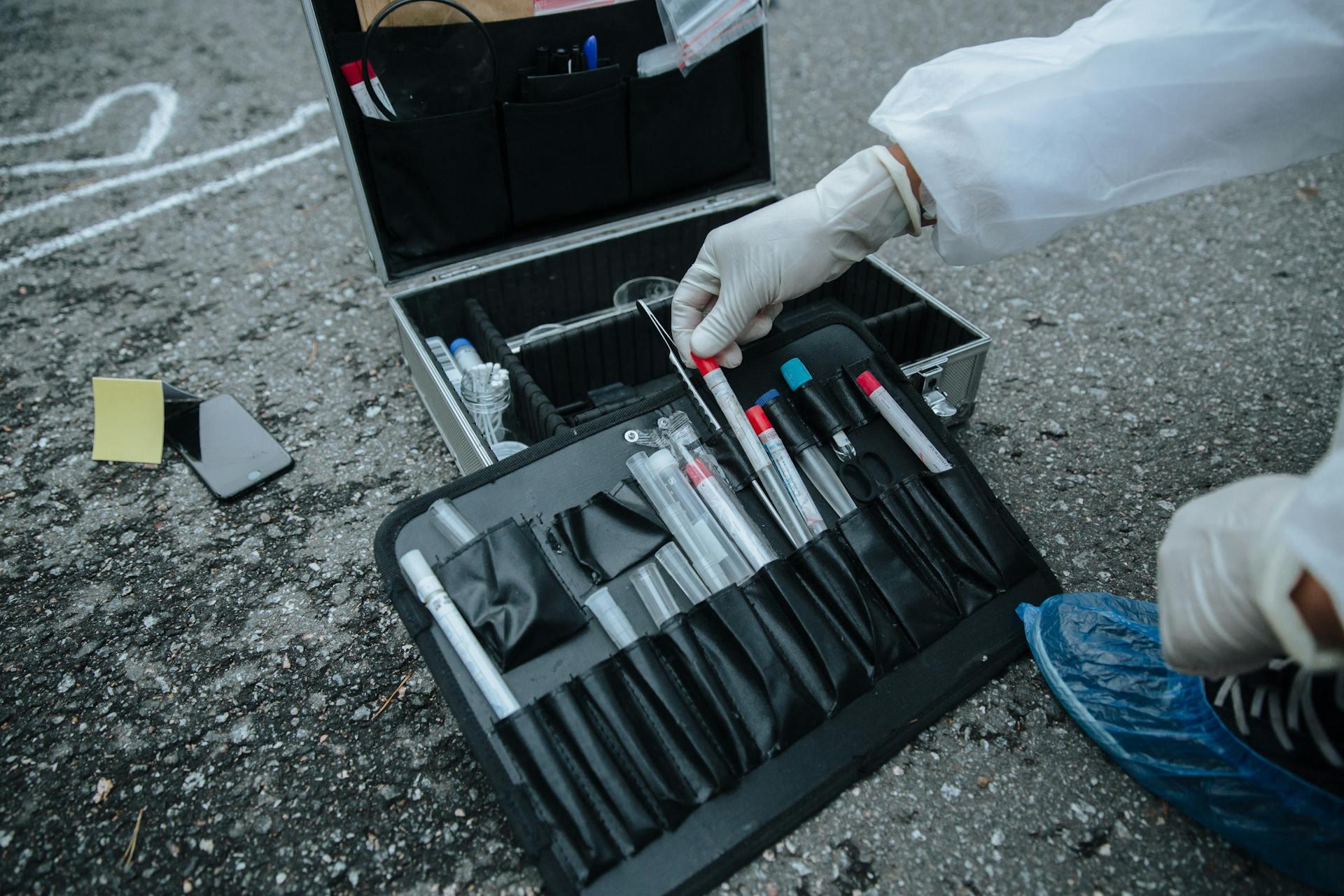 a forensic scientist using scientific collection tools to take evidence from a crime scene