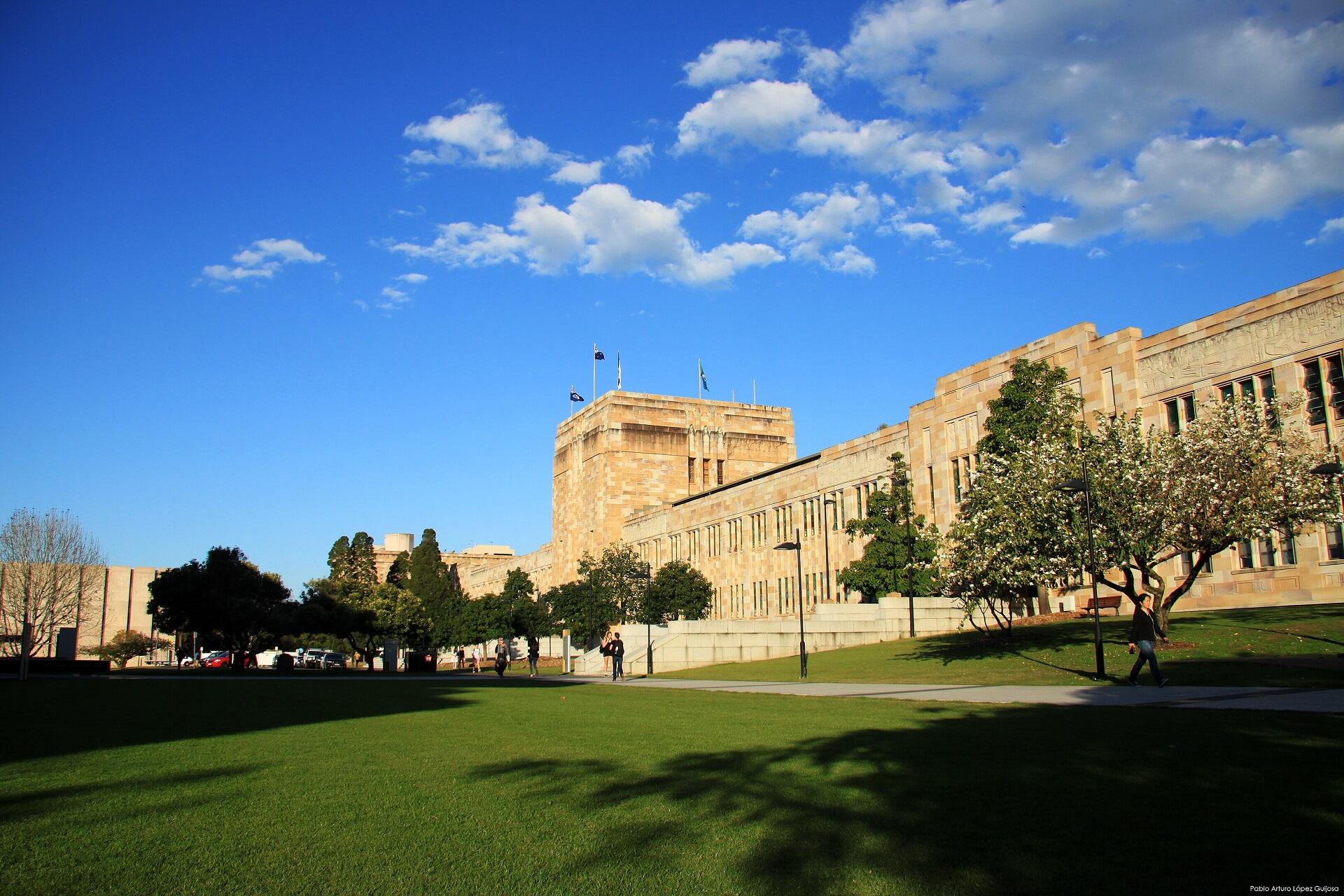 A light-coloured stone building and open green space on a sunny day. 