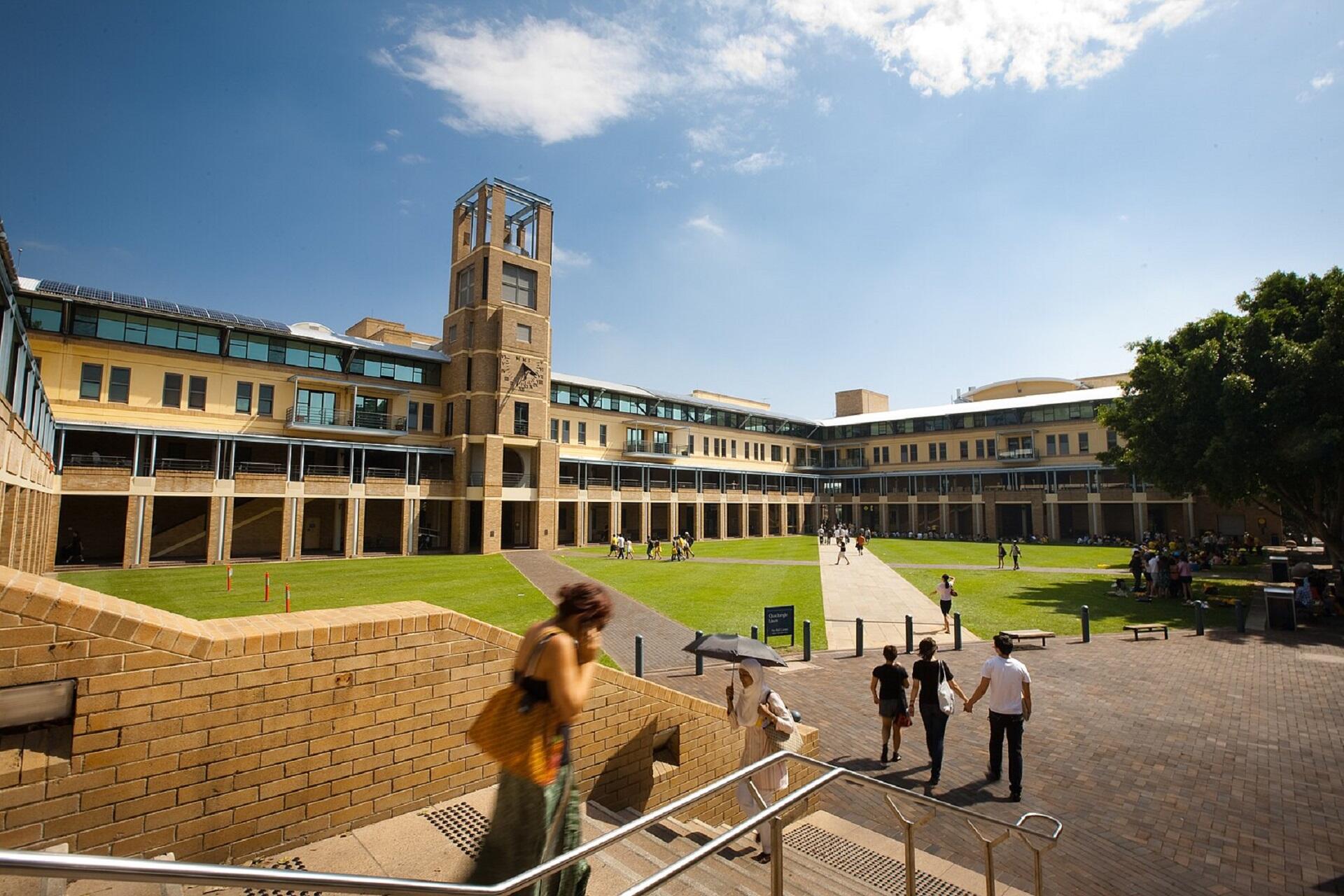 A stone building framing a quadrangle on a sunny day.