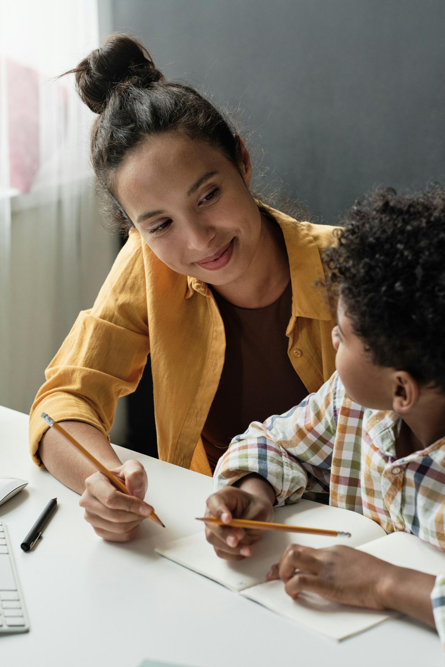 A woman sitting next to a child at a desk.