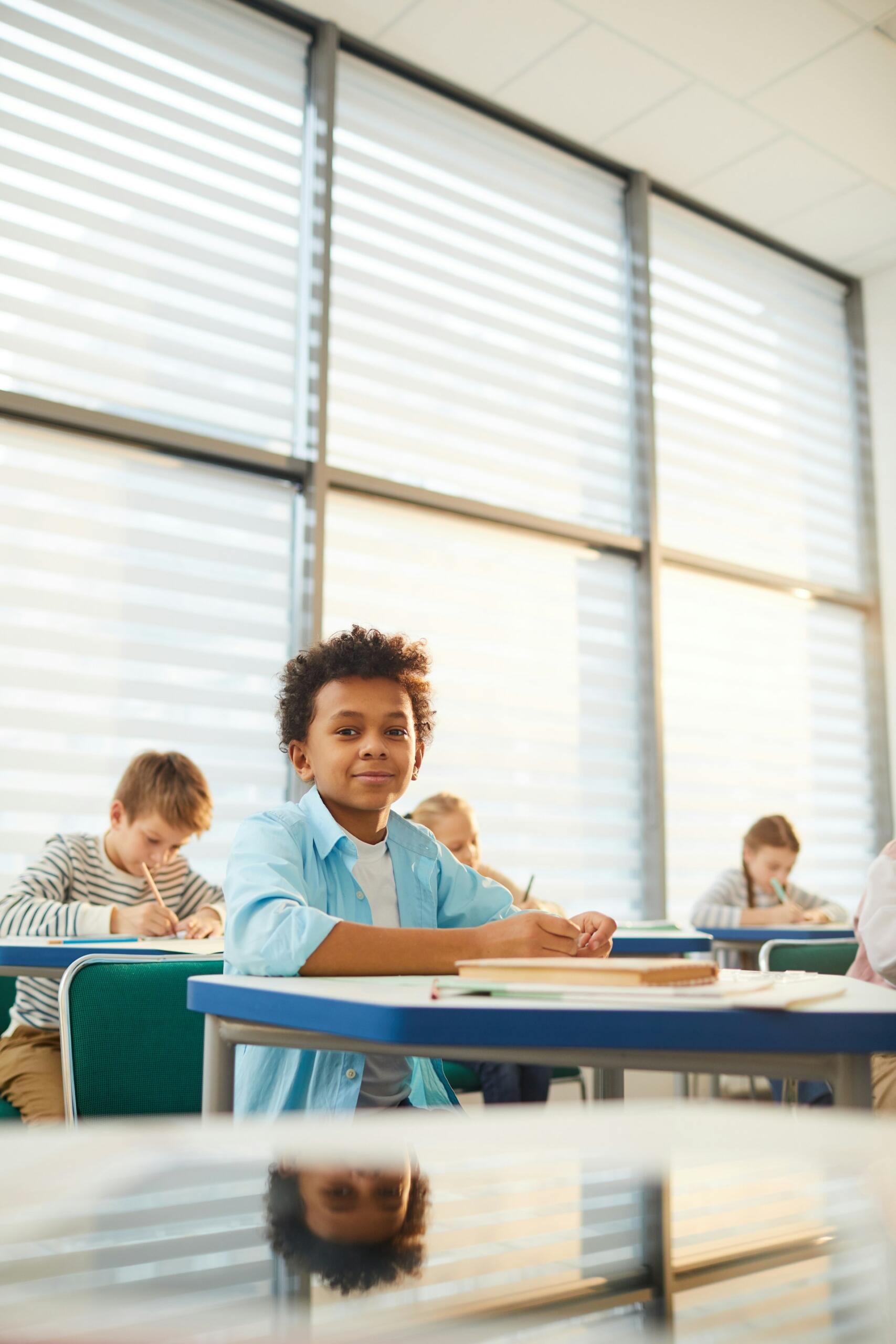 Students in a classroom in front of a large bank of windows.