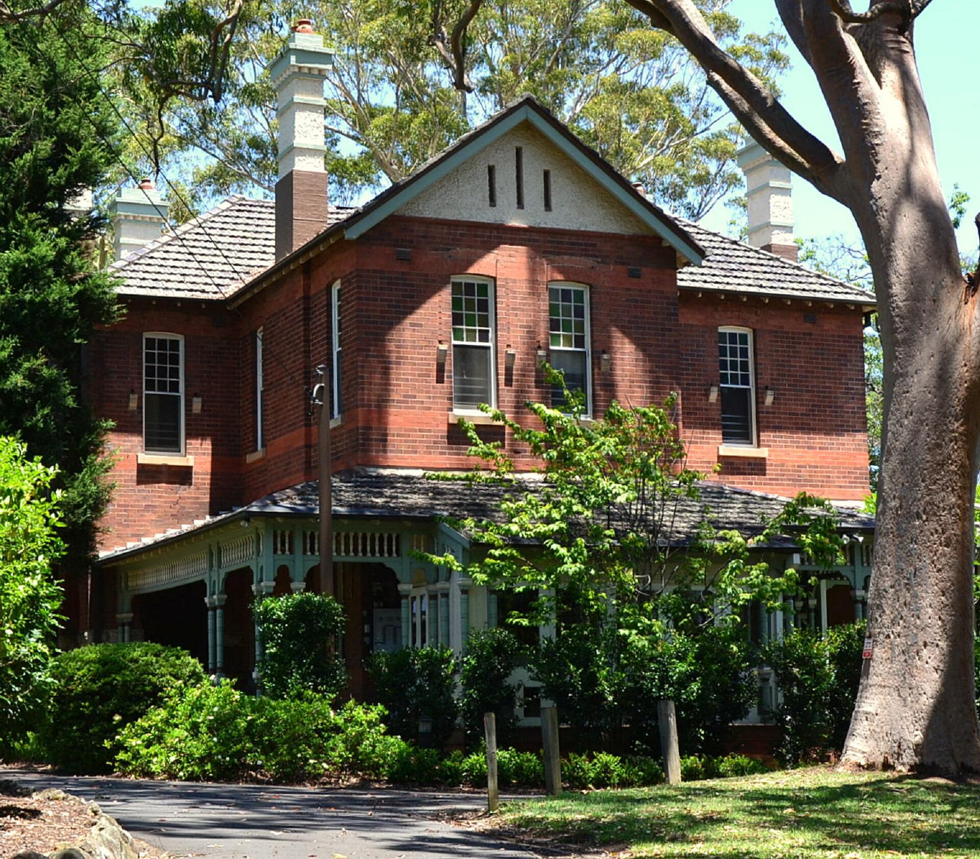 A brick building behind greenery on a sunny day.