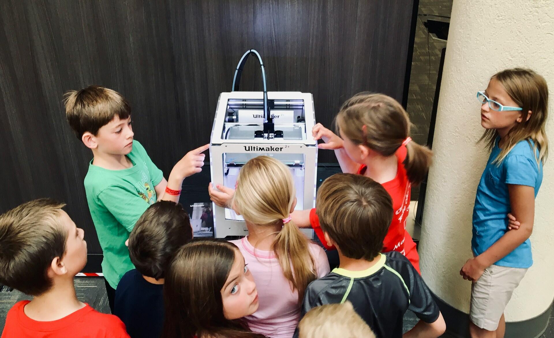 Students gather around a three-D printer. 