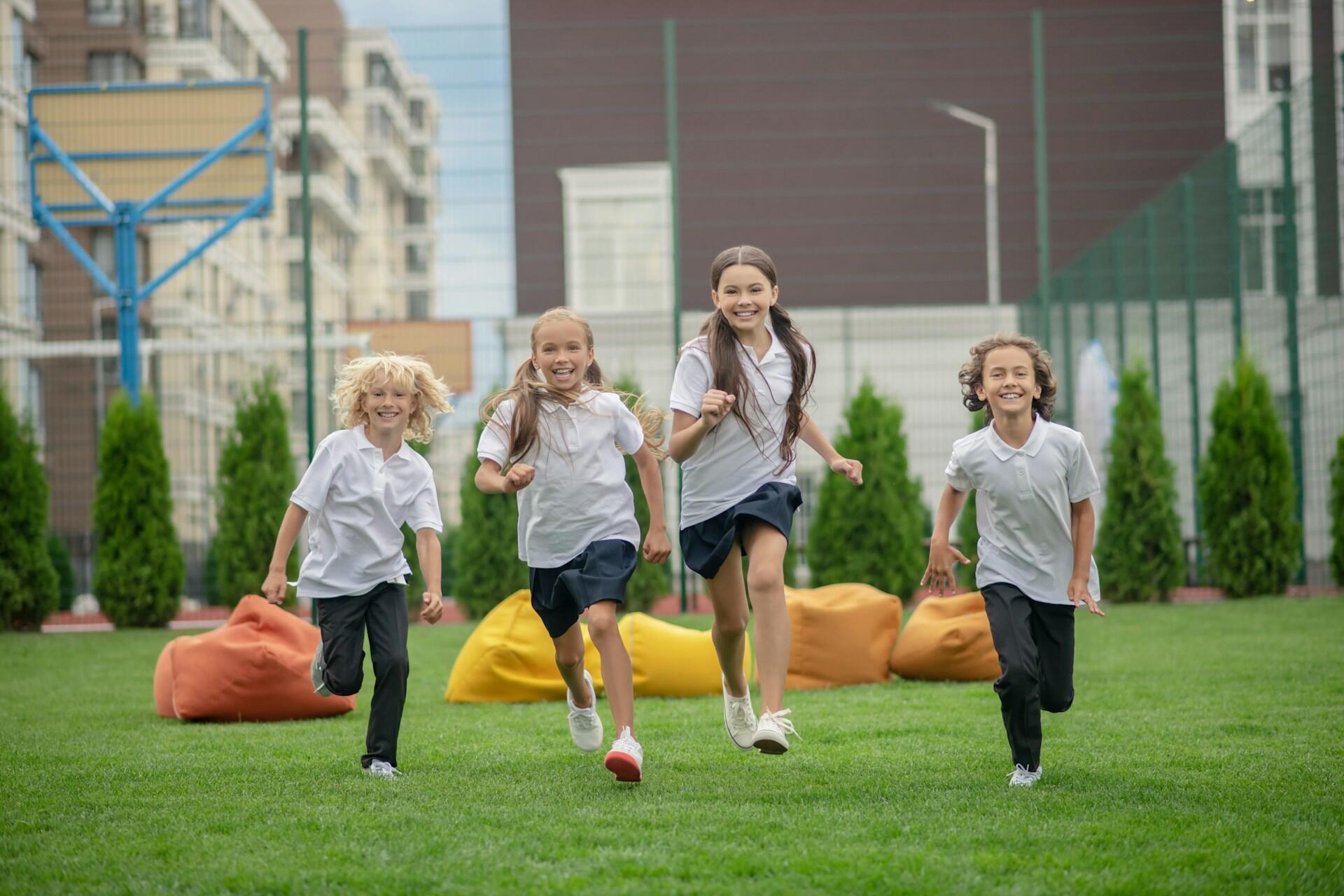 Four children in school uniforms running.