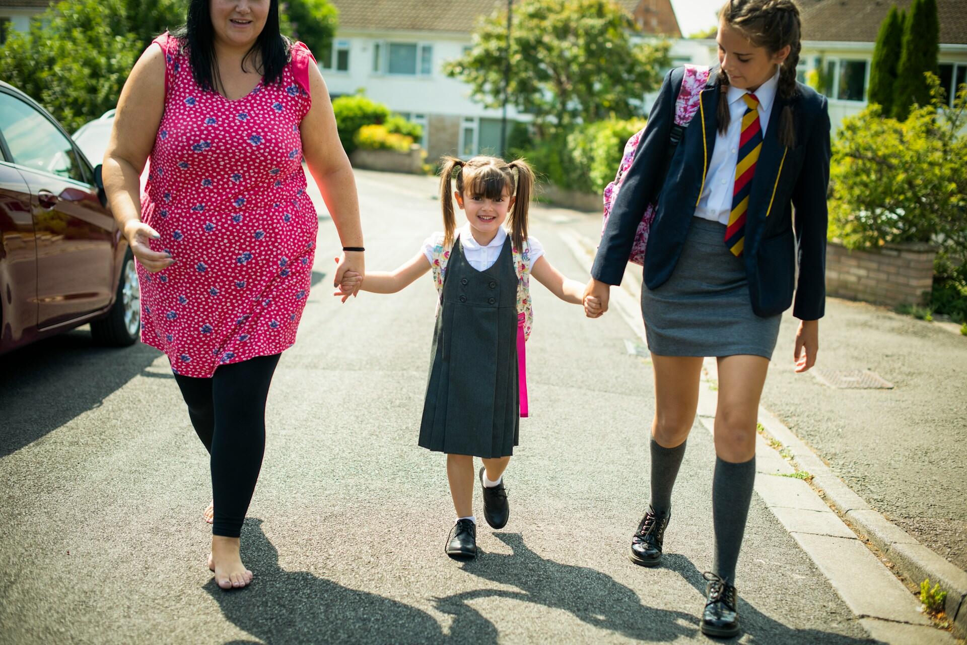 A woman walking with two girls in school uniform. 
