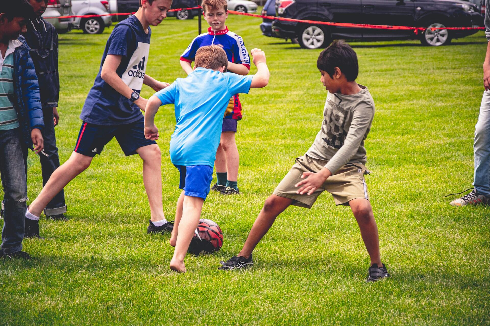 Boys playing football on grass.