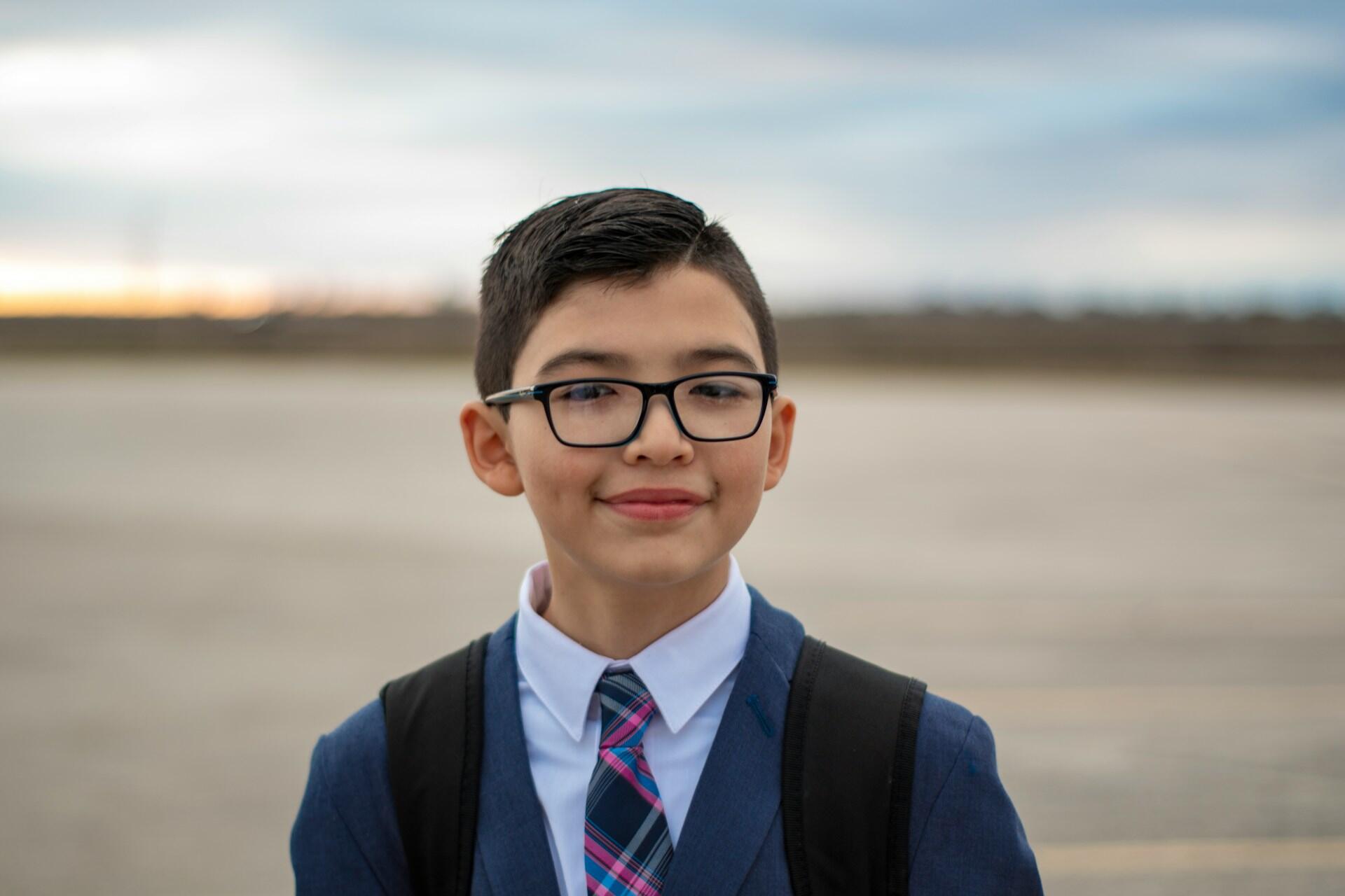 A boy wearing glasses and a school uniform.