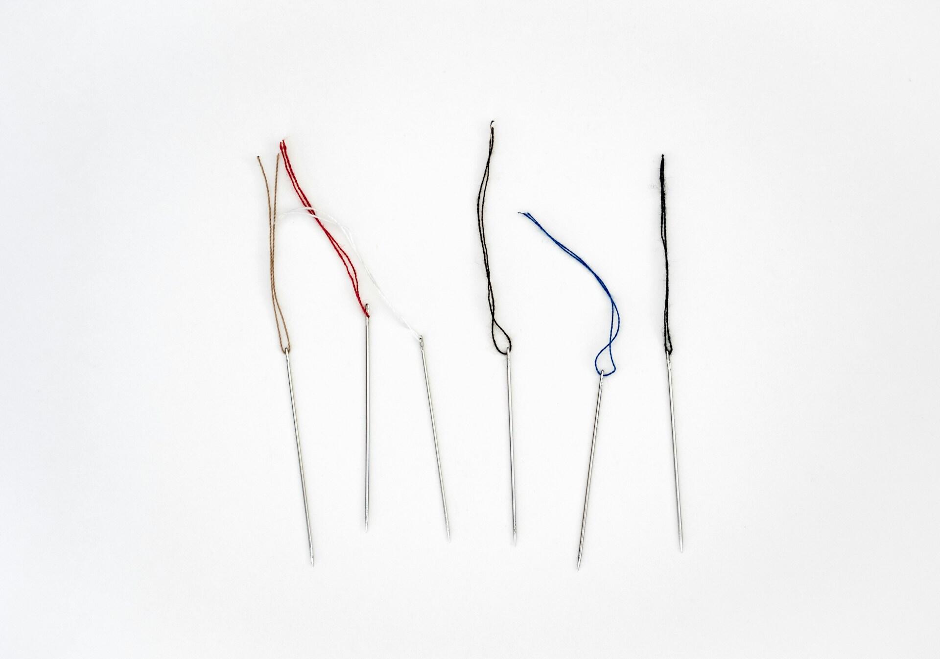 Sewing needles with snippets of thread.