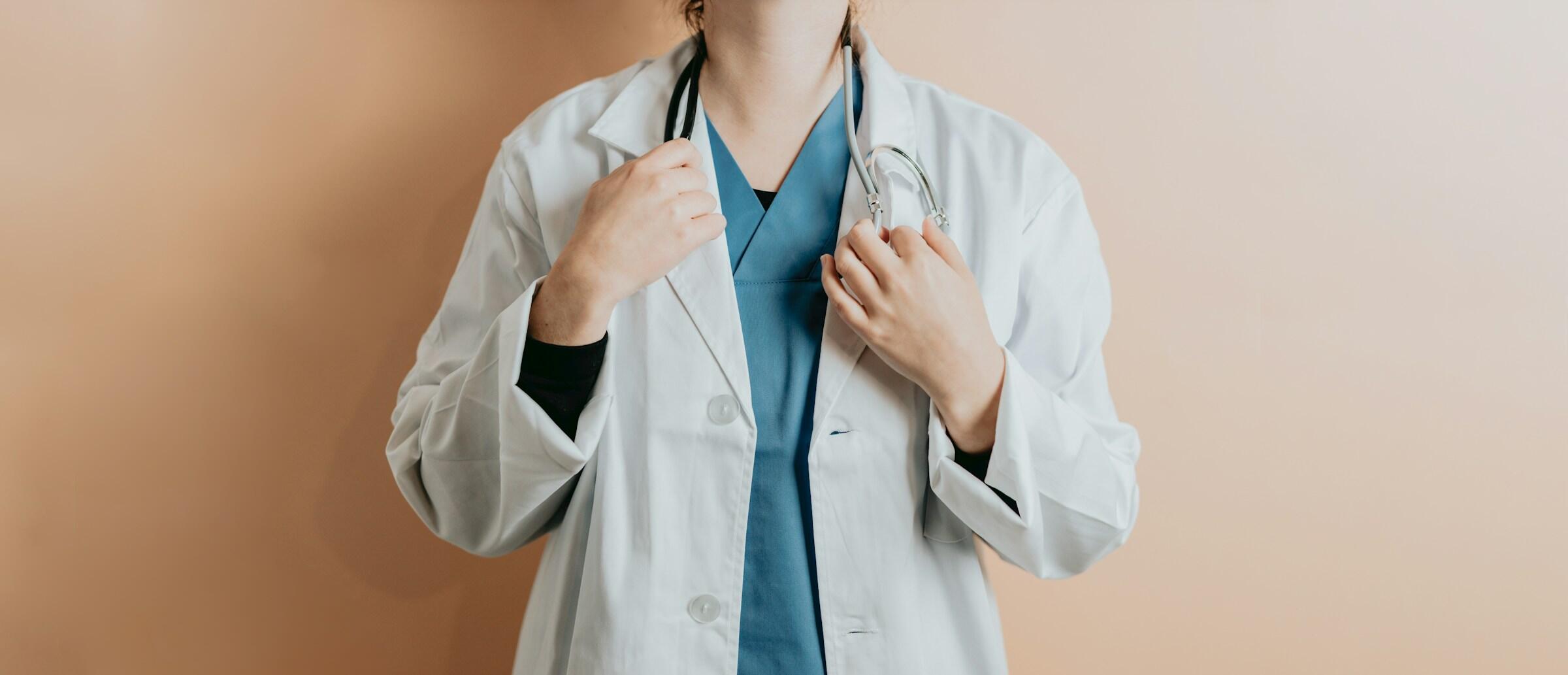 A nurse in a white coat and scrubs.