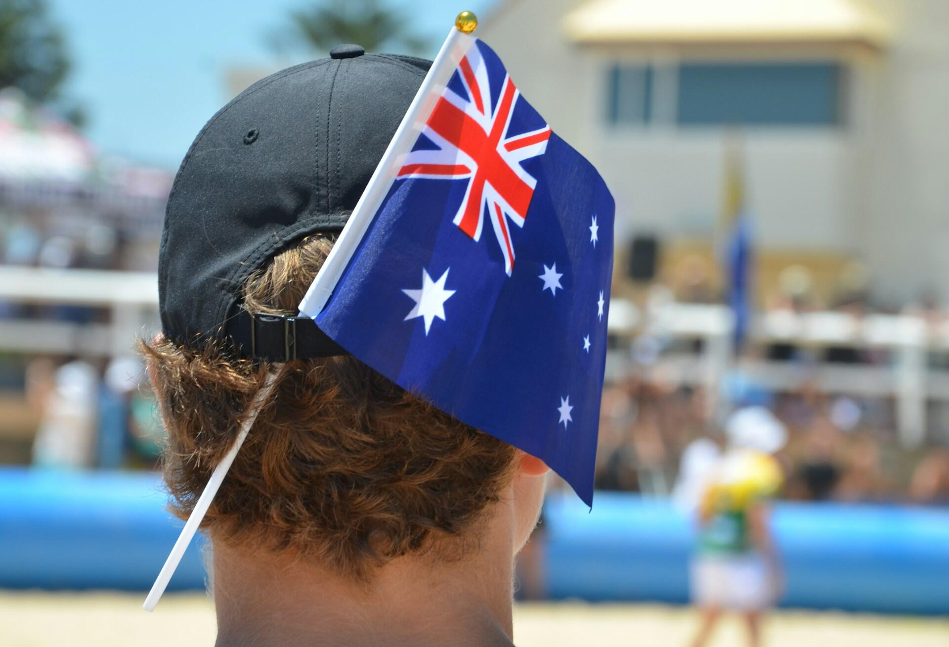A man wearing a blue hat with an Australian flag tucked in it.