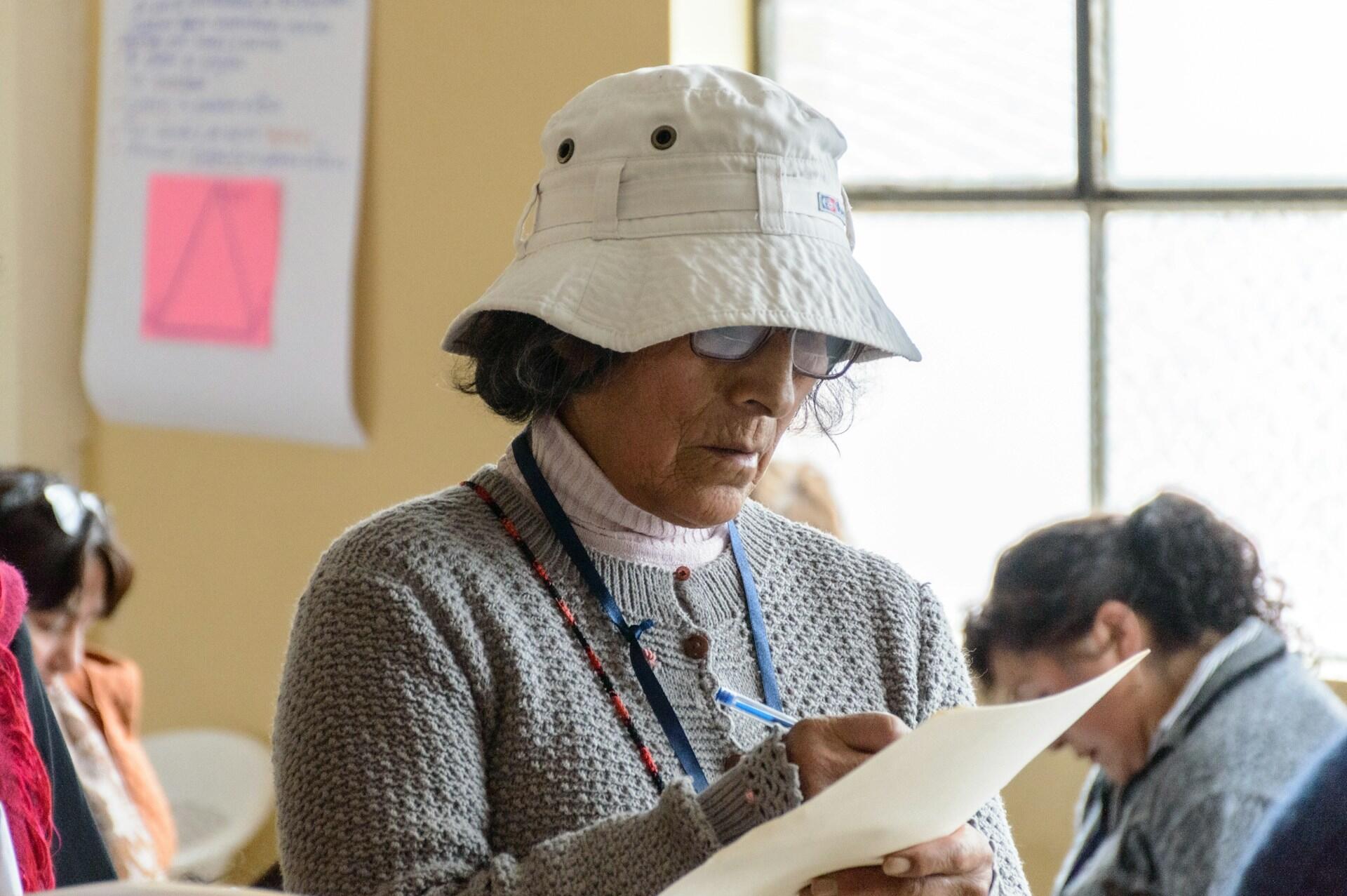 A person wering a hat and holding a clipboard.