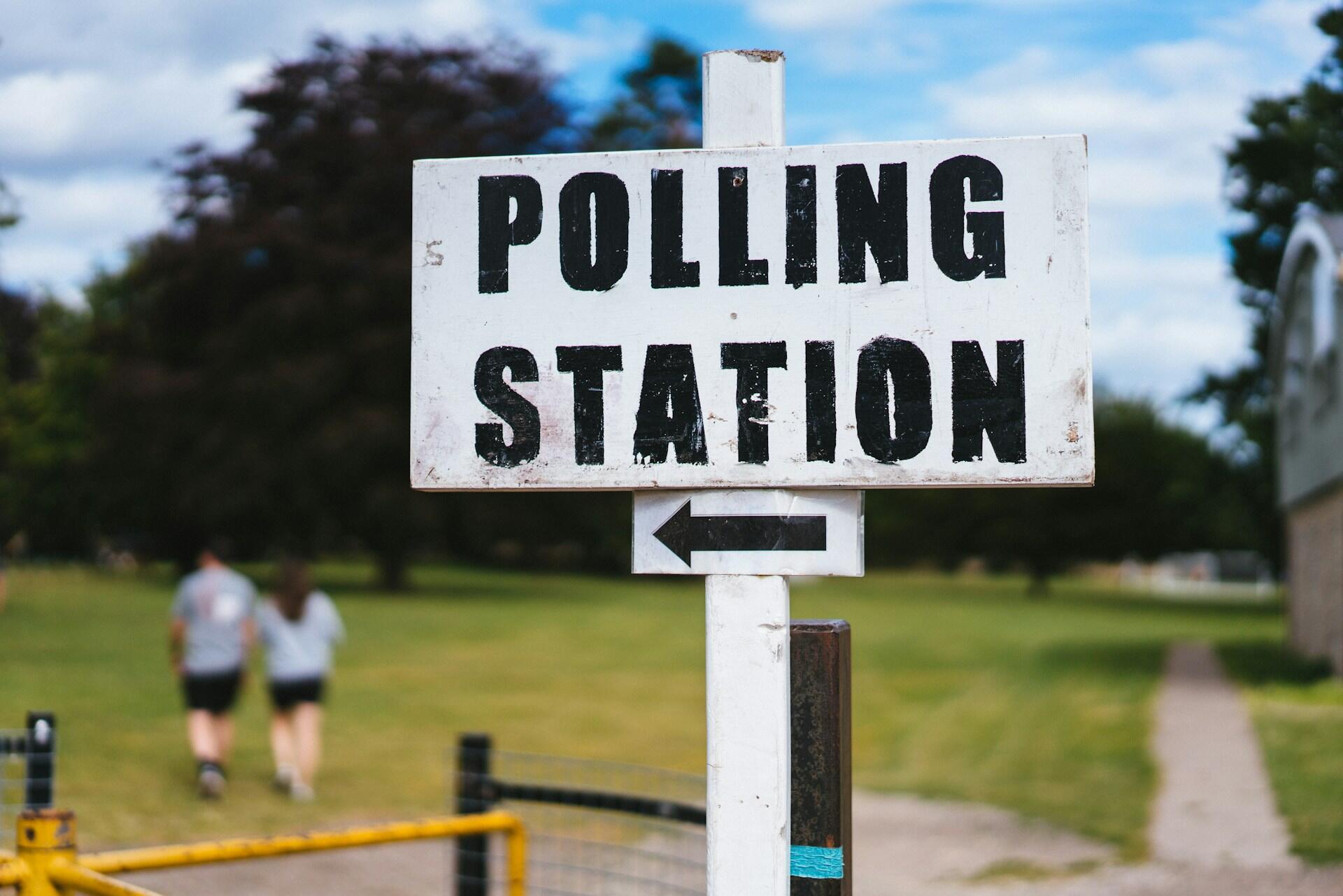 A black and white sign pointing to a polling station.