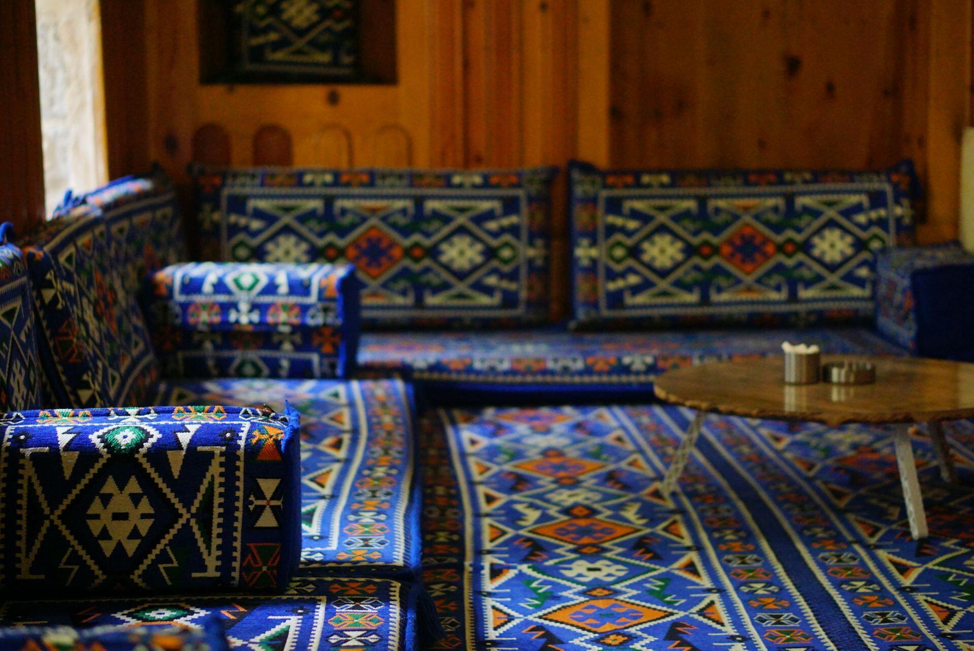 a living room in Turkiye featuring thin cushions resting on the floor with backs and arm rests