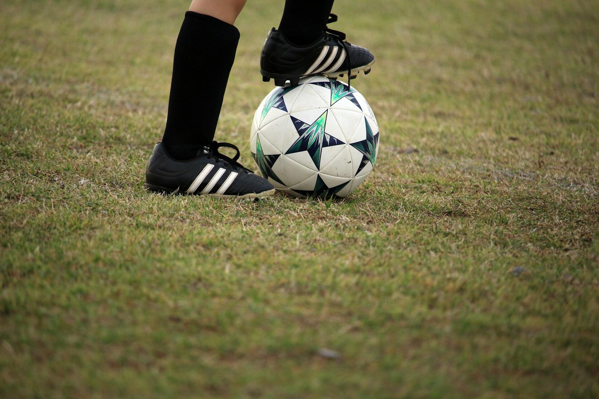 A football player with their foot on the ball.