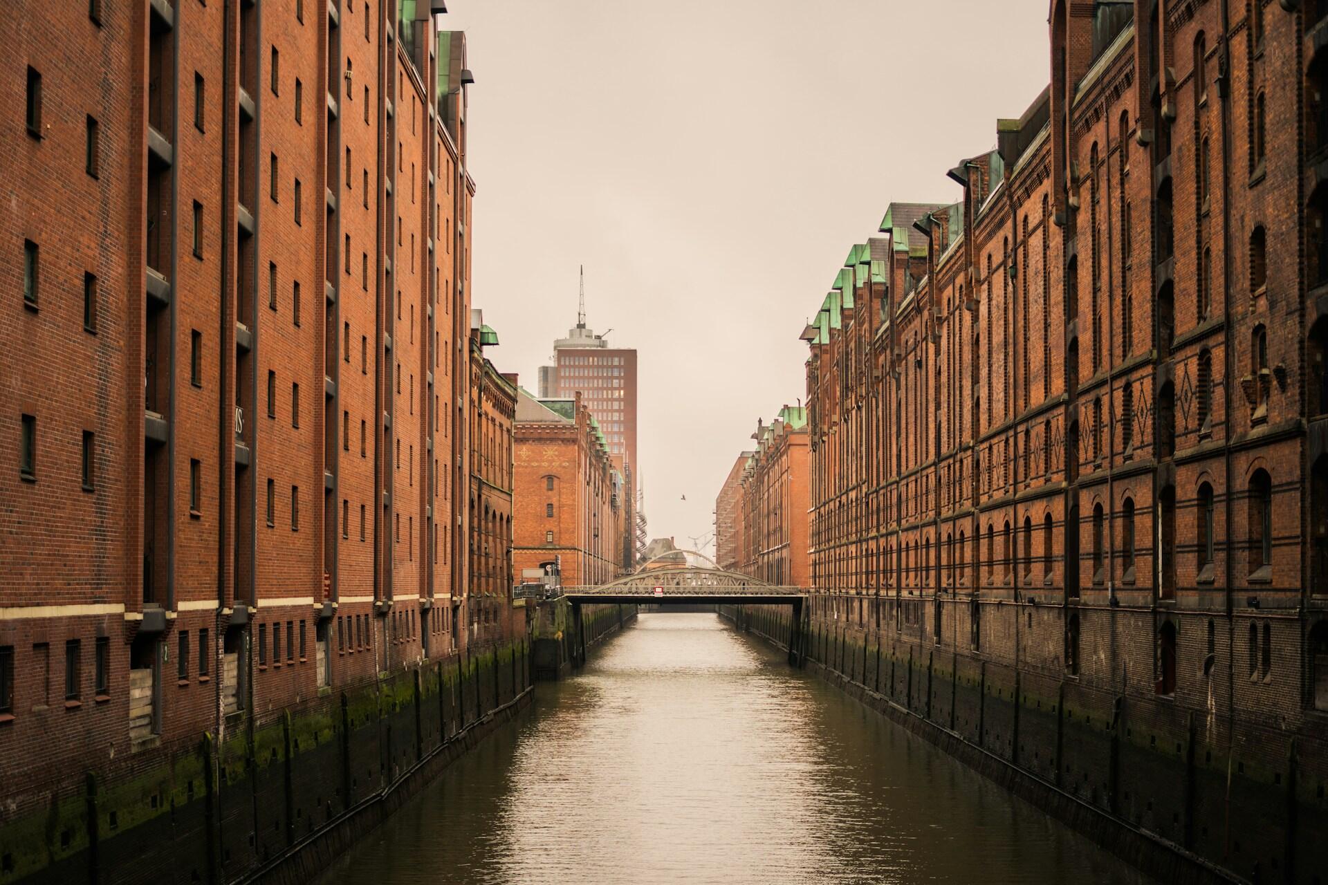 View of a narrow canal flanked by brick buildings in Hamburg, Germany.
