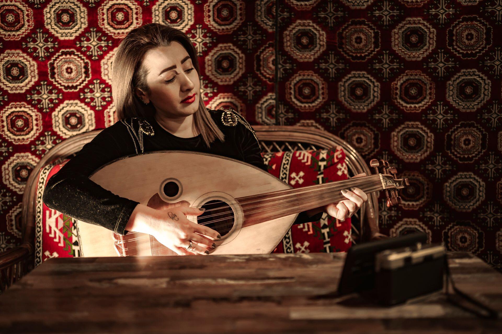 a lute player in a room with ornate traditional wall hangings and upholstery