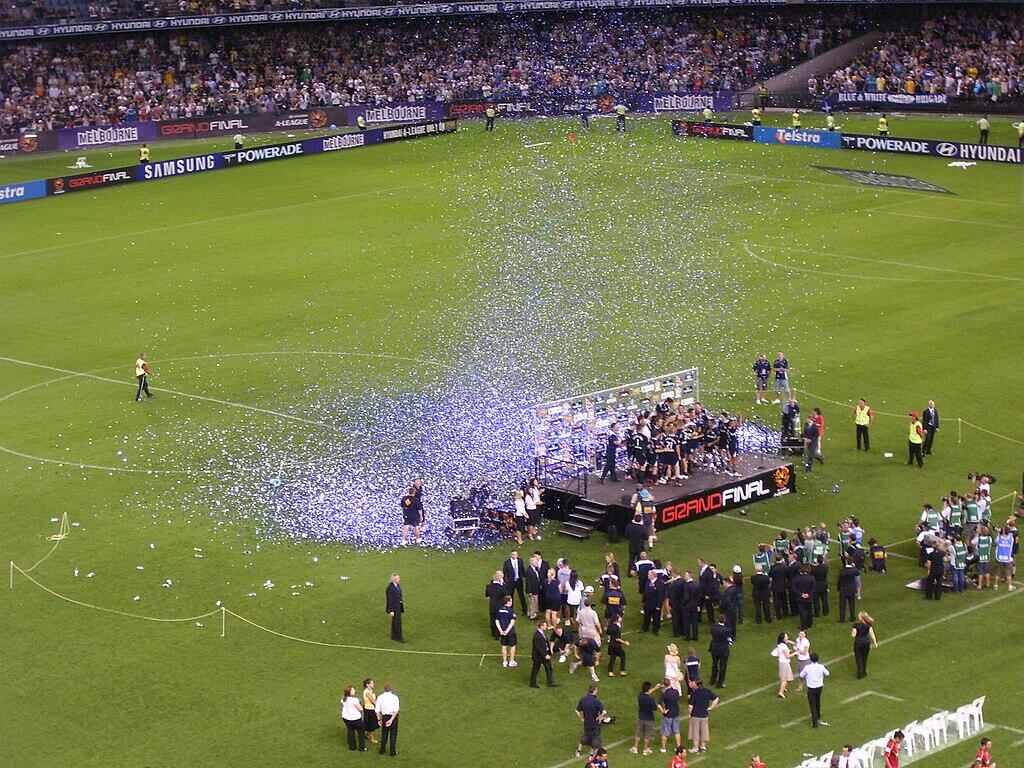 Melbourne Victory FC celebrates on a podium, surrounded by confetti, after their 2007 A-League Grand Final victory.