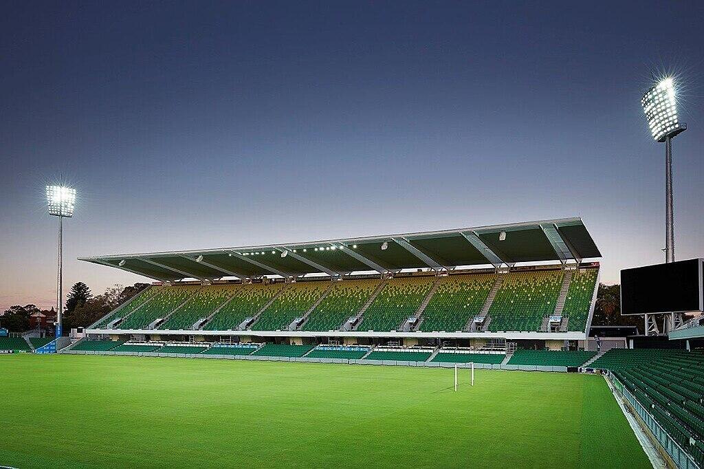 Perth Rectangular Stadium, home of Perth Glory FC, with green seating under a clear twilight sky.