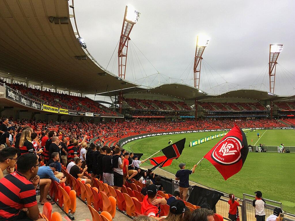 A lively soccer match between Western Sydney Wanderers and Perth Glory at a packed stadium in Sydney.