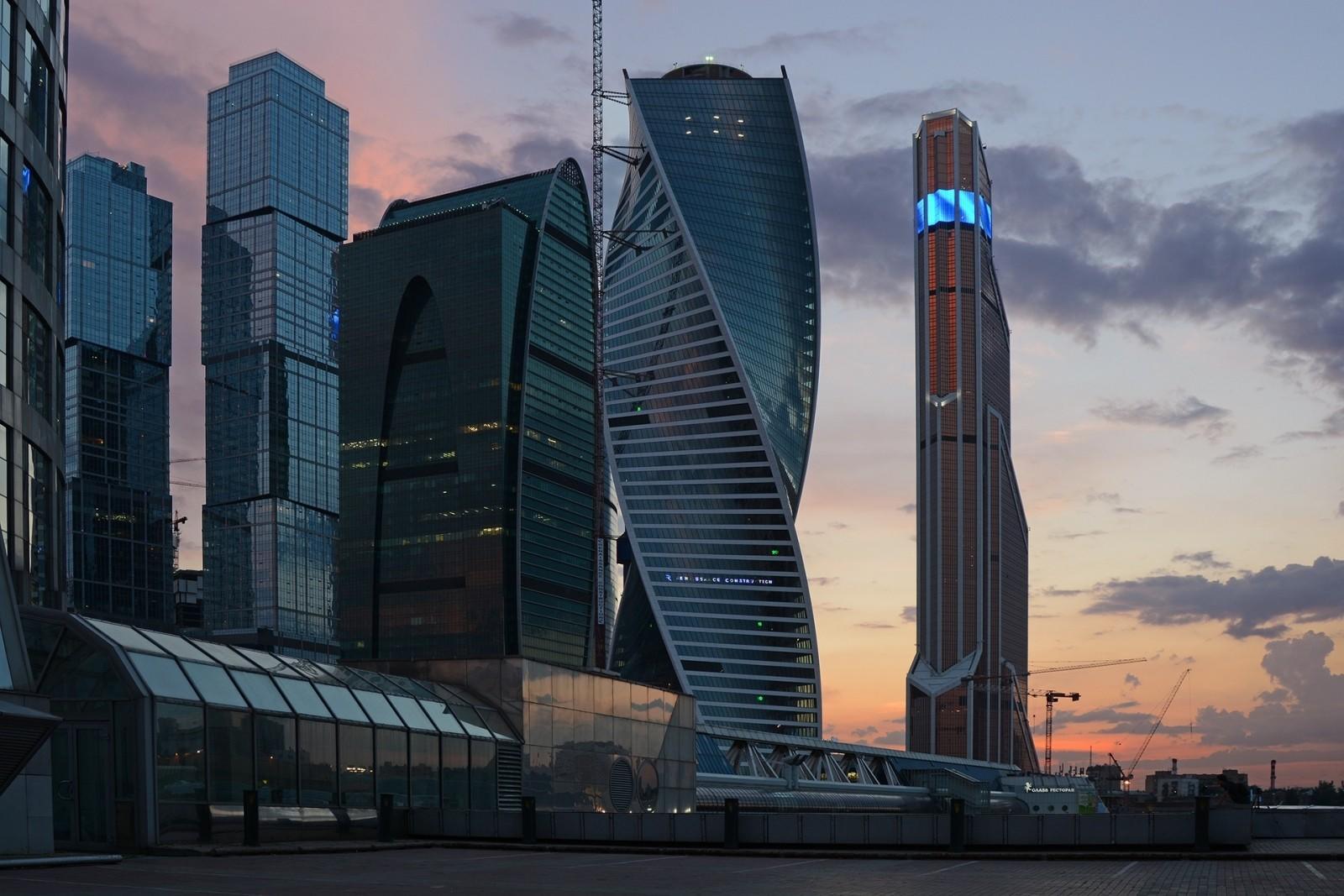 Modern skyscrapers dominate the skyline, silhouetted against a vibrant sunset.
