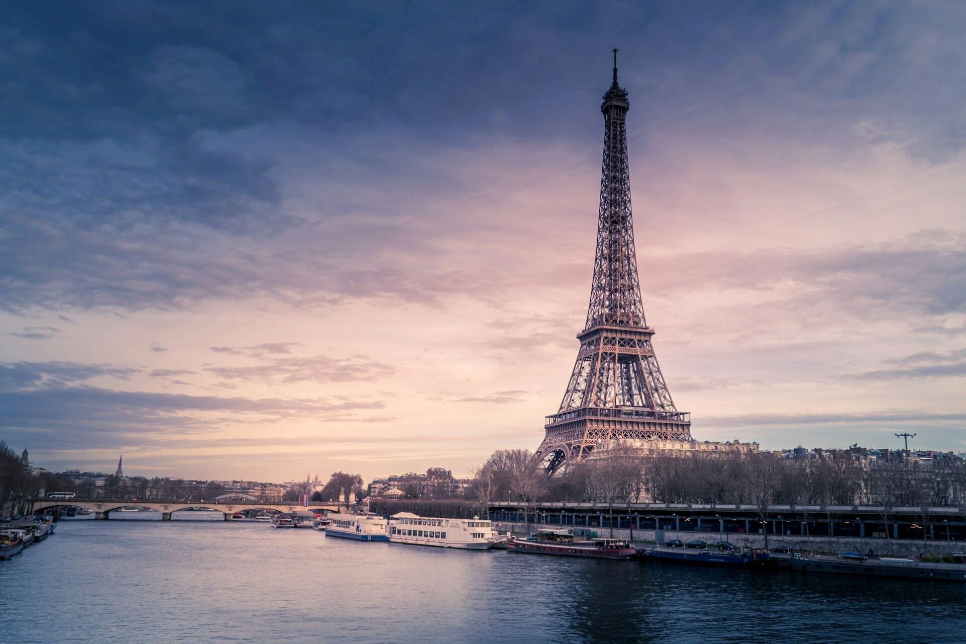 Eiffel Tower beside the River Seine with boats and buildings along the waterfront at sunset