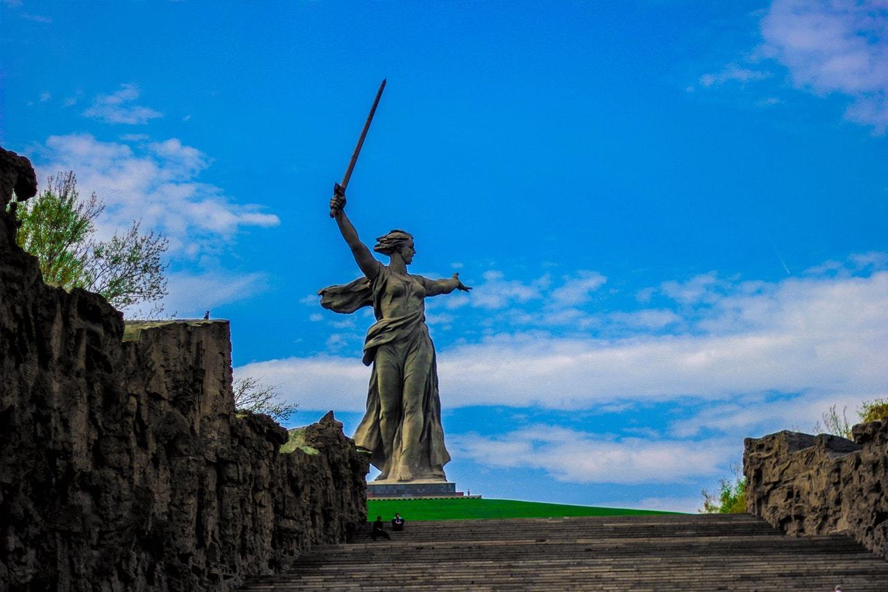 A towering statue of a woman holding a sword against a blue sky.