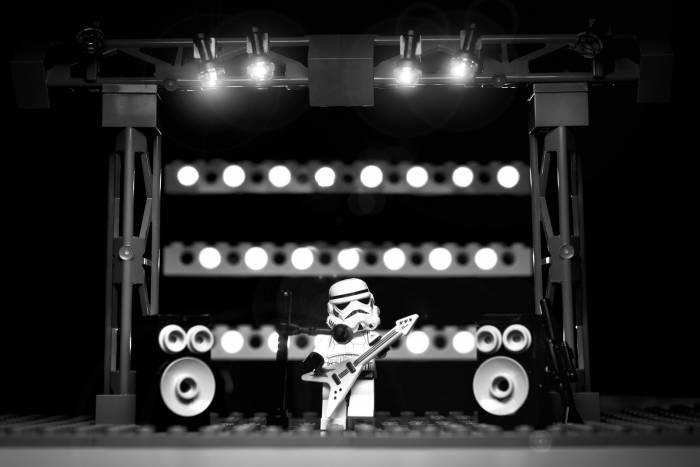 A Lego Star Wars figure with a guitar on stage.