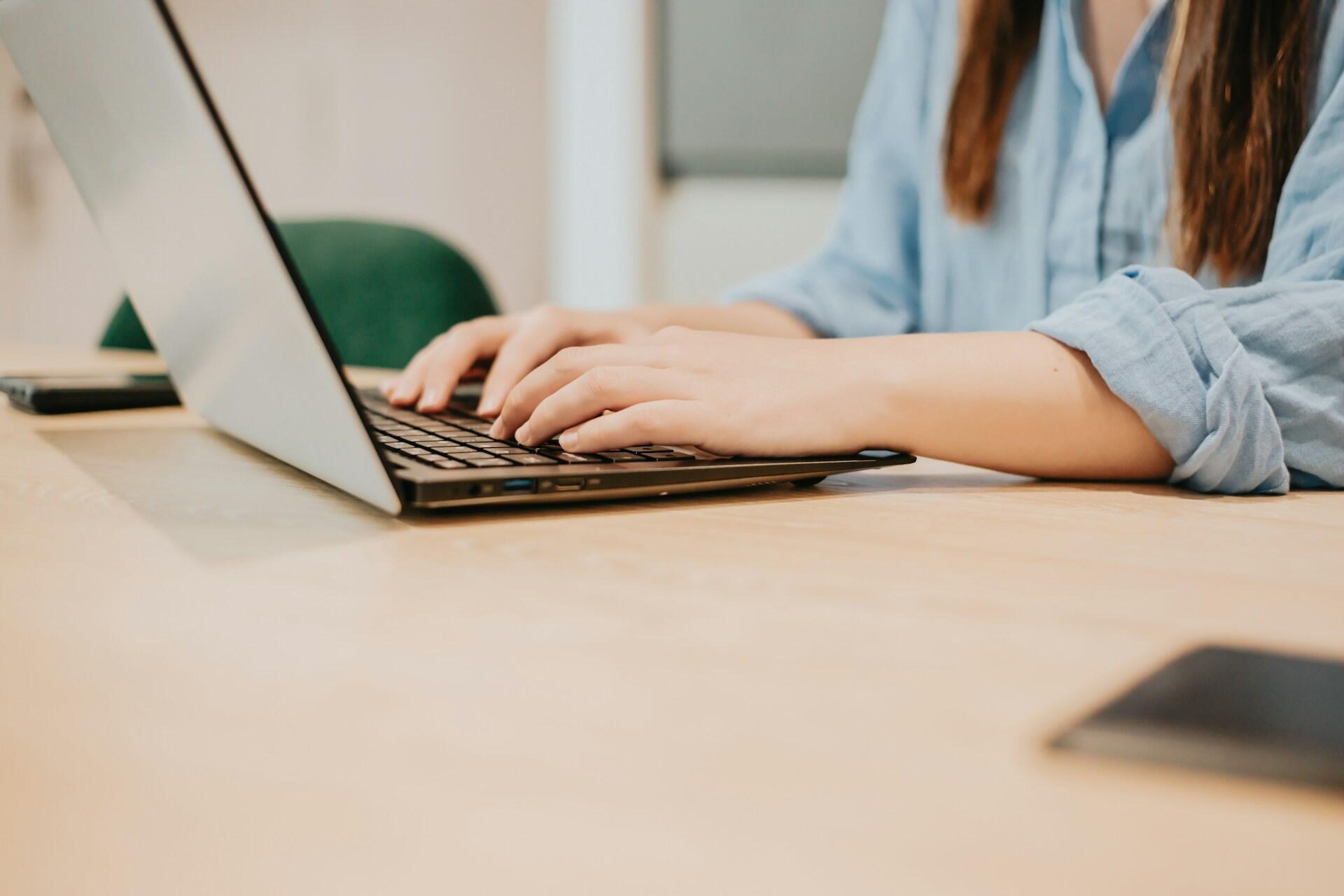 A person wearing a blue shirt working on a computer.