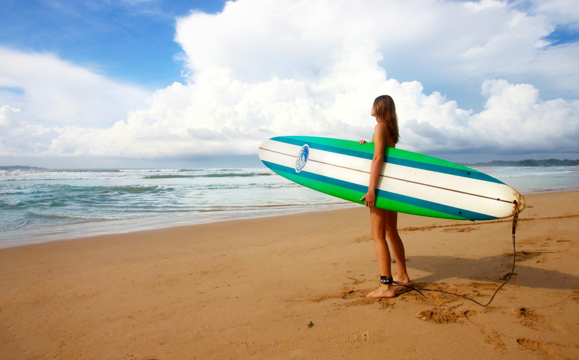 A surfer and their board standing on the beach.