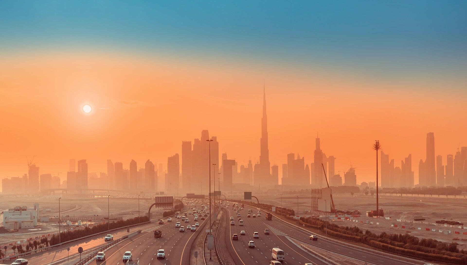 Silhouetted skyline of Dubai at sunset, featuring the Burj Khalifa.