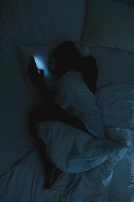 A person using their phone in the dark before bed.