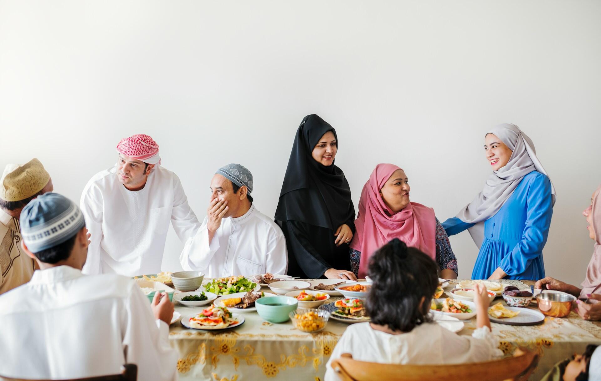 A Muslim family enjoying a meal around a table filled with diverse dishes.