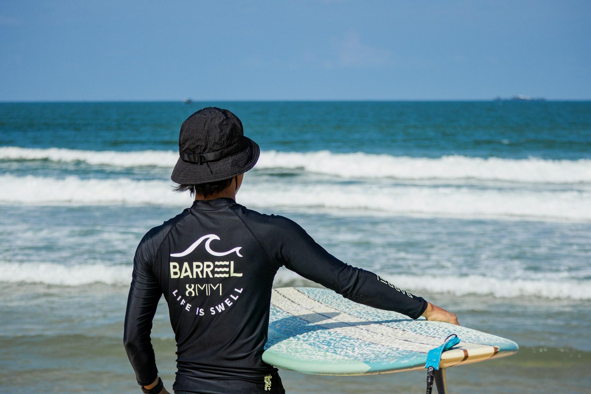 A surfer wearing a black long-sleeved surfing shirt.